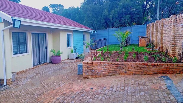 Um imóvel residencial com um caminho de acesso pavimentado, um canteiro de jardim de tijolos e uma casa azul.