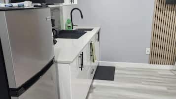 Eine moderne Küche mit integriertem Mikrowellenherd, einer Spüle und einem Edelstahl-Kühlschrank.