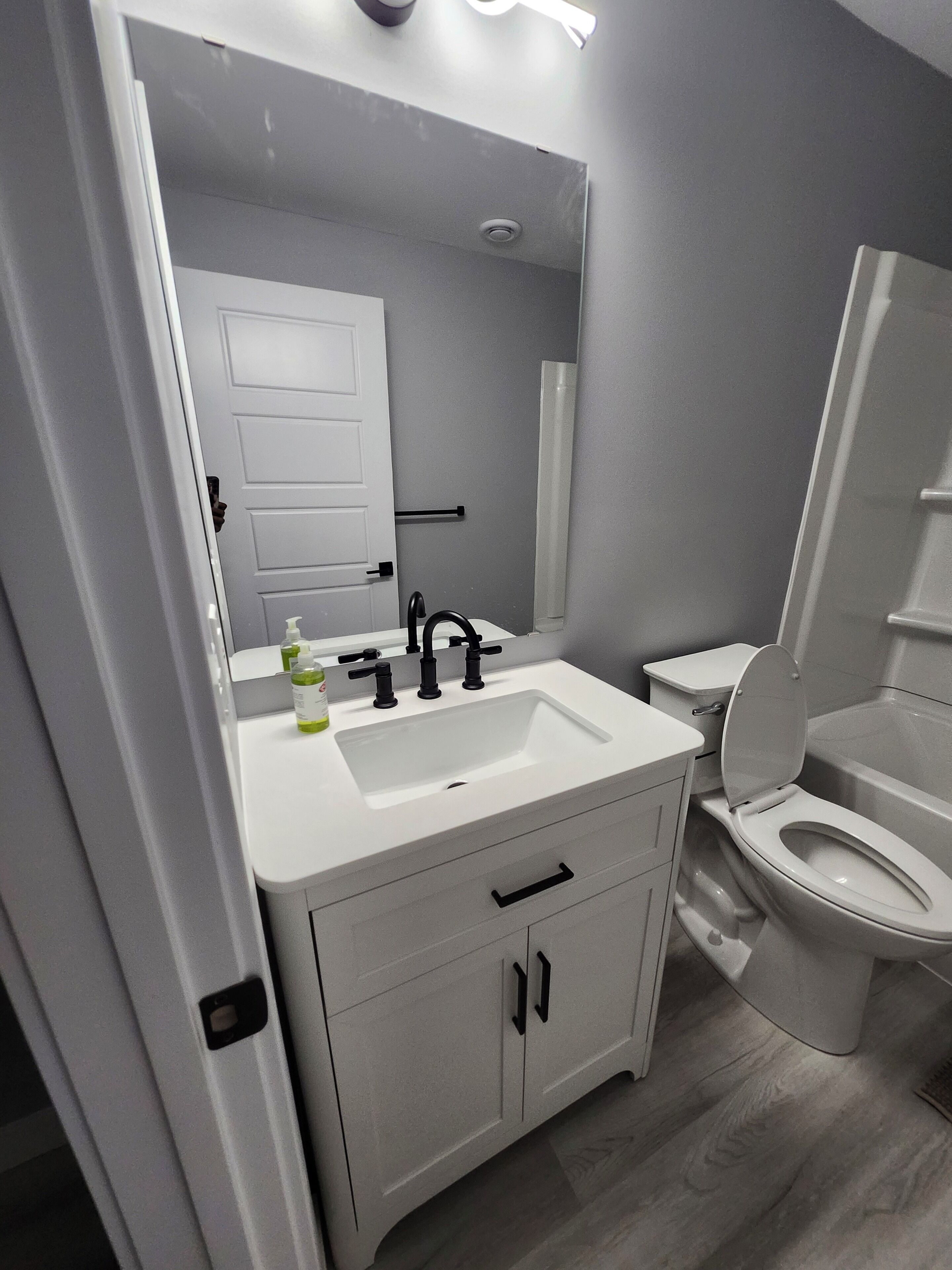 Un bagno moderno con lavandino bianco, rubinetto nero e un water.