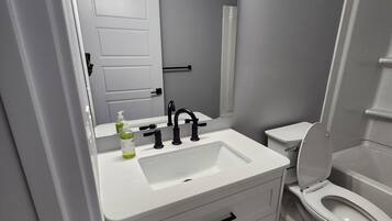 Un bagno moderno con lavandino bianco, rubinetto nero e un water.