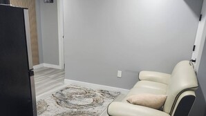 Un salon moderne avec un canapé, un tapis et un réfrigérateur.