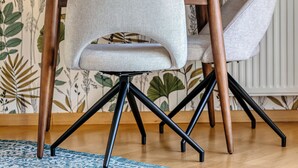 Comedor con una mesa, dos sillas y un papel tapiz floral.