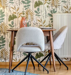 Ein Essbereich mit Tisch, zwei Stühlen und einer Wand mit botanischem Wandpapier.
