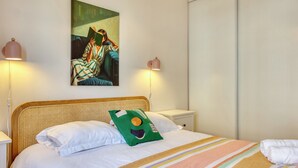 Un dormitorio con cama, un cuadro, lámparas de noche y una mesita de noche.