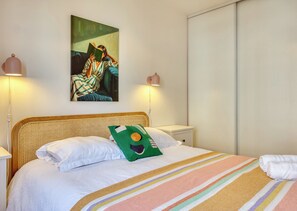Ein Schlafzimmer mit einem Bett, einem Gemälde, Nachttischlampen und einem Nachttisch.