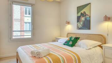 Une chambre à coucher avec un lit, une fenêtre, un tableau et une lampe de chevet.