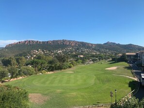 A golf course with a mountain backdrop, a road with a speed limit sign, and residential buildings.
