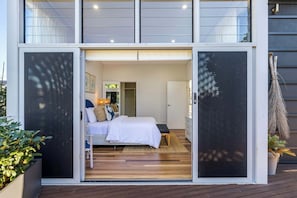 Ein modernes Schlafzimmer mit Bett, Nachttisch und Blick ins Zimmer.