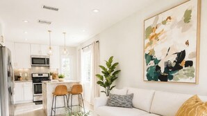 Een moderne woonkamer met een witte bank, een bijzettafeltje en een schilderij aan de muur.