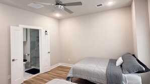 A bedroom with two beds, a ceiling fan, a door leading to a bathroom, and a wooden floor. - Houston Hub- Family Getaway, Garage & Yard (Houston)