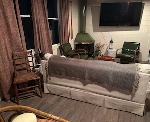 Ein gemütliches Wohnzimmer mit einer Couch, Sesseln, einem Kamin und einem Fernseher.