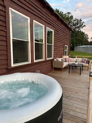 Eine Holzterrasse mit Whirlpool, einer Sitzecke und einem Tisch.