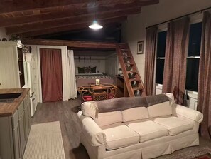 Un salon confortable avec un canapé, une table à manger et un escalier menant à une chambre en mezzanine.
