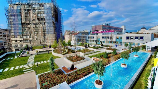 Un edificio moderno con area piscina, che include una piscina rettangolare e una fontana circolare.