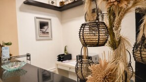 Un'area reception con un bancone nero, un quadro appeso alla parete e piante decorative essiccate.