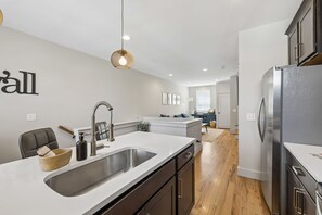 A modern kitchen with a central island, stainless steel appliances, and a hanging light fixture. - Some Things Just Go Better Together - Nash homes sleep 20! (Nashville)