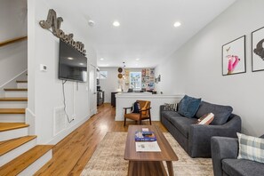 Ein modernes Wohnzimmer mit Treppe, einer Couch, einem Couchtisch und einer Küche im Hintergrund.