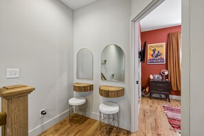 Een badkamer met twee wastafels, een spiegel en een houten kruk.