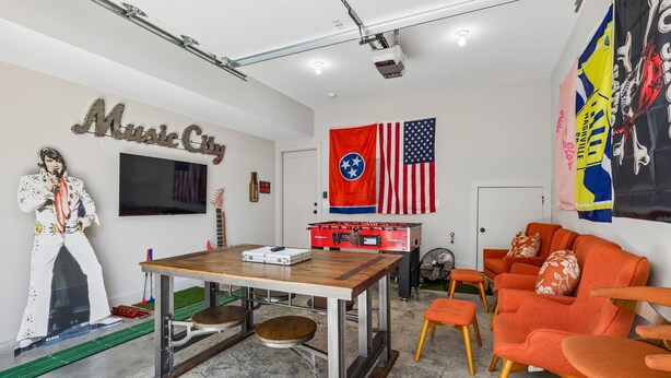 A room with a table, chairs, a flag, and a wall decoration. - Some Things Just Go Better Together - Nash homes sleep 20! (Nashville)