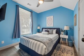 A bedroom with a bed, a nightstand, a lamp, a ceiling fan, and a window with curtains. - Some Things Just Go Better Together - Nash homes sleep 20! (Nashville)