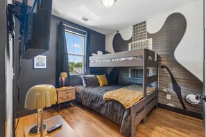 Een slaapkamer met een stapelbed, een raam, een nachtkastje en een lamp.