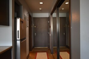 A hallway with a refrigerator, a door, and a red and beige rug. - Perfect Frisco Location: Cozy Studio Steps from Main Street (Frisco)
