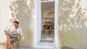 A man sitting outside reading a newspaper, with a dining area visible inside the building. - Casa François – Appartement rénové à 100 m de la plage de Calvi (Calvi)