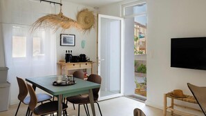 A dining area with a table, chairs, and a television on the wall. - Casa François – Appartement rénové à 100 m de la plage de Calvi (Calvi)