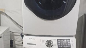 Deux machines à laver superposées, dotées de panneaux de commande et d’une porte transparente.
