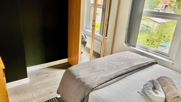 Une chambre à coucher avec un lit, une fenêtre, un radiateur et une vue sur l’extérieur.