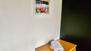Une pièce avec une commode en bois, un tableau encadré accroché au mur et une serviette posée sur la commode.