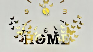 Une horloge murale ornée d’une inscription « HOME » et de motifs de papillons.