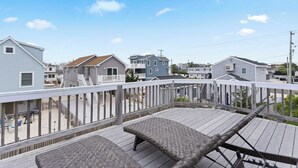 A wooden deck with two cushioned seating areas, surrounded by a white railing, overlooking a residential neighborhood. - 1 Block to Beach, 4BR Ship Bottom LBI, Sleeps 8, Walk to All (Ship Bottom)