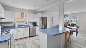 A modern kitchen with white cabinets, a stainless steel refrigerator, and a blue countertop. - 1 Block to Beach, 4BR Ship Bottom LBI, Sleeps 8, Walk to All (Ship Bottom)