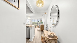 A modern kitchen with a large island, a dining area with a round table, and a large mirror on the wall. - Dune Dreams just steps to the beach (Hutchinson Island)