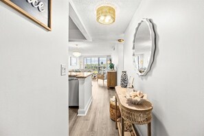 Een moderne keuken met een groot eiland, een zithoek met een ronde tafel en een grote spiegel aan de muur.