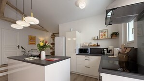 Uma cozinha moderna com ilha central, armários brancos e parede de destaque em pedra.