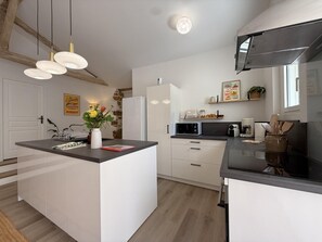 Eine moderne Küche mit Kochinsel, weißen Schränken und einer Wand mit Naturstein-Akzenten.