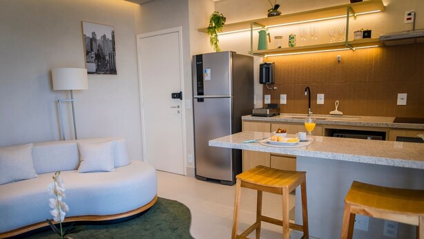 Una cocina moderna con refrigerador integrado, un comedor con taburetes y un sofá.