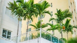 Un edificio moderno con balcón, palmeras y un jardín.