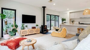 Ein modernes Wohnzimmer mit Kamin, Sofa, Couchtisch und großen Fenstern.