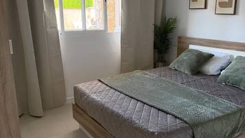 Une chambre à coucher avec un lit, des rideaux, une fenêtre et deux tableaux encadrés accrochés au mur.