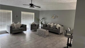 A living room with two sofas, a coffee table, a ceiling fan, and a dining area with chairs and a table. - House in Houston (Houston)