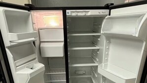 An open refrigerator with multiple shelves and compartments, a freezer section, and a control panel. - House in Houston (Houston)