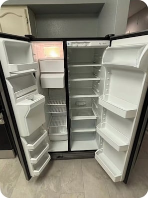 Ein offener Kühlschrank mit mehreren Ablagen und Fächern, einem Gefrierfach und einer Bedienblende.