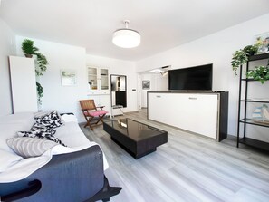 Un salon moderne avec un canapé, une table basse et un téléviseur à écran plat.