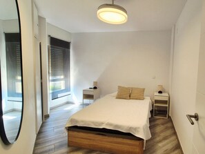 Une chambre à coucher avec un lit, des tables de chevet, une lampe et un miroir.