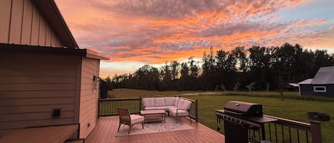 A deck with a grill, a sofa, and a chair.