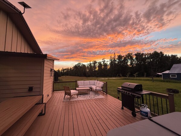 A deck with a grill, a sofa, and a chair.