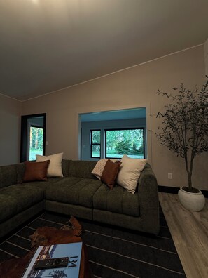 A living room with a sectional sofa, a coffee table, and a potted plant.